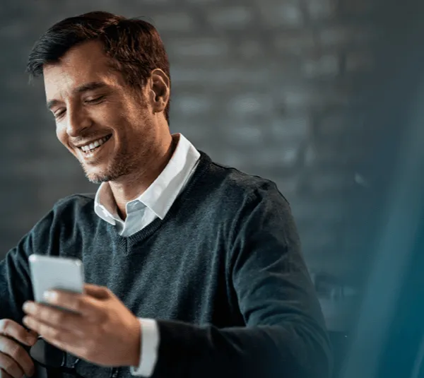 Empresário sorrindo enquanto acompanha a empresa pelo ERP Know-How no smartphone